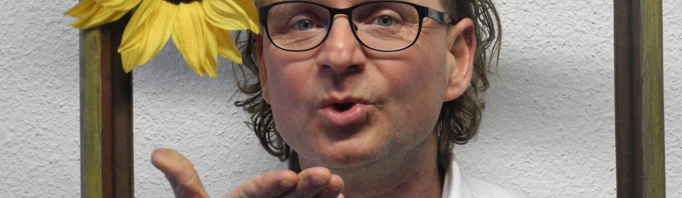 Ralf Käppler mit Handkussgeste und Sonnenblume